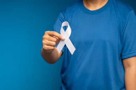 A female hand is holding a white ribbon on a blue background photo