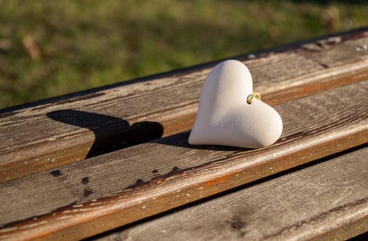 A figurine of a stone heart lies on a wooden bench photo
