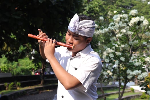 Portrait of Balinese Asian man playing traditional bamboo flute in outdoor park photo