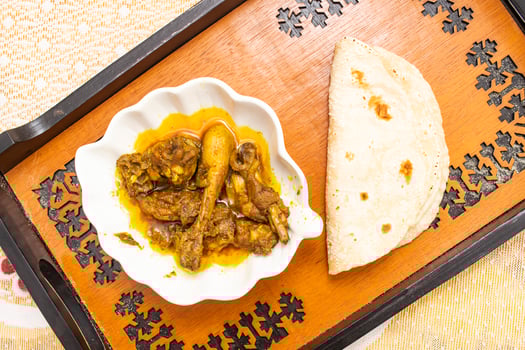 Spicy Desi Chicken Curry with Roti served on tray dish isolated on dinning table top view of bangladeshi food photo