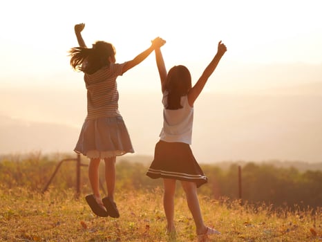 Two little girls are happily playing on meadow during a summer sunset. Family love with colorful sunset. photo