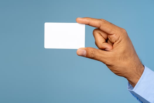 Businessman holding empty white business card, selective focus on hand isolated on blue background photo