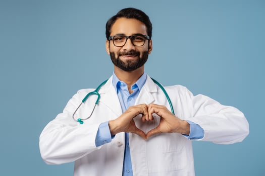 Indian doctor wearing white coat and stylish eyeglasses having stethoscope showing hearth with hands photo