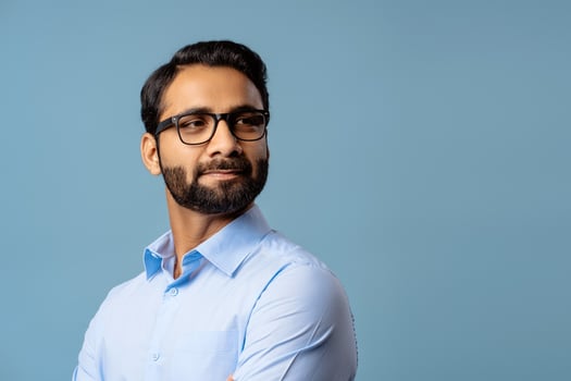 Portrait of successful, handsome Indian man wearing stylish eyeglasses, looking away on copy space photo