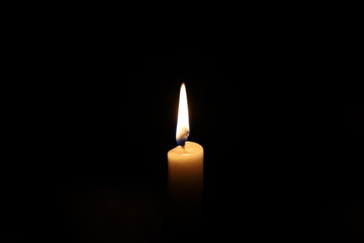 Paraffin candle in complete darkness, light in the darkness photo