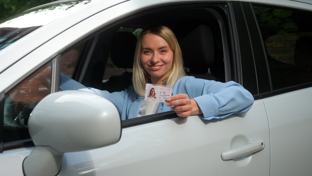 Glad Caucasian vehicle buyer woman owner sit in car smiling lady female showing driver license automobile driving school certificate test drive in city girl businesswoman driver achieve education auto photo