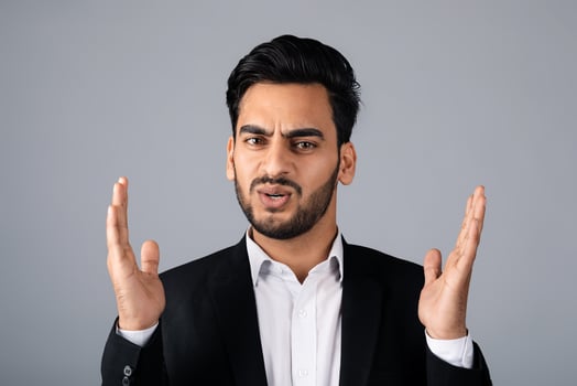 A Middle Eastern businessman in a suit conveys surprise with his hands raised. He is in a studio setting, focusing on entrepreneurial concepts and corporate strategies. photo