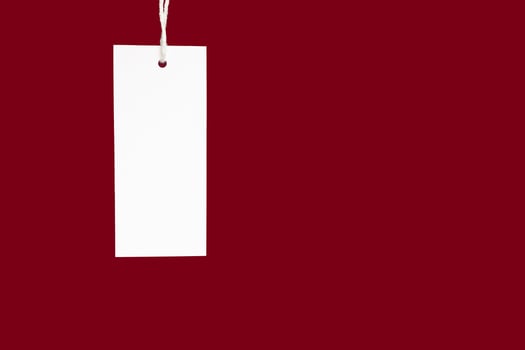 A blank white label or price tag against a red background photo