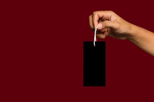 Hand holding a blank white label or price tag against a red background photo