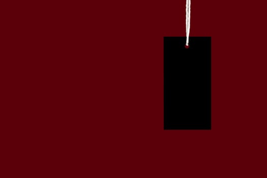A blank black label or price tag against a red background photo