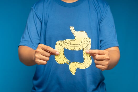 Close-up of hand holding a colon symbol while standing on a blue background photo