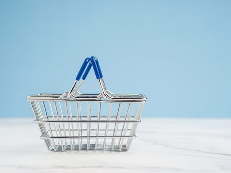 An empty mini shopping cart over a marble floor with a light blue background photo