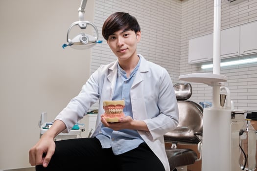 Portrait of one young smart Asian male dentist in uniform, Thai professional dental occupation worker, teeth healthcare, hygiene work in dental clinic hospital, happy smile, and looking at camera. photo