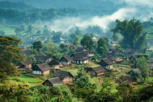 Misty mountain village with traditional houses nestled in lush green valley. photo