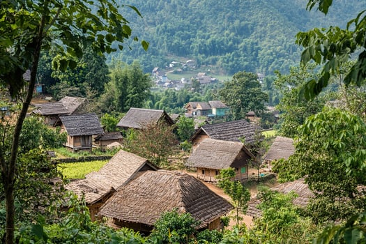 Mountain village with traditional thatched-roof houses nestled amongst lush greenery. photo