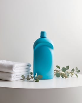 Blue plastic detergent bottle mockup standing on white surface with clean towels and eucalyptus branches photo