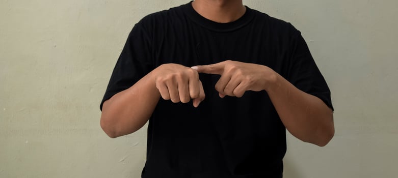 Young man showing word TIME in sign language on gray background photo