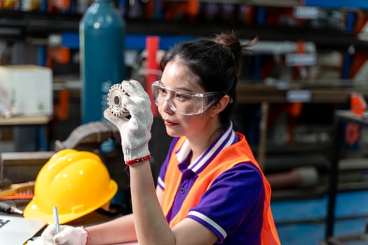 Closeup Asian woman industrial engineer hold and looking example small gear to working designing mechanical parts engineering photo