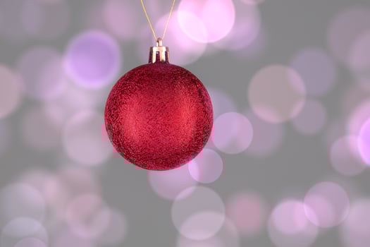 A red Christmas ball on a gray background with spots of pink bokeh. photo
