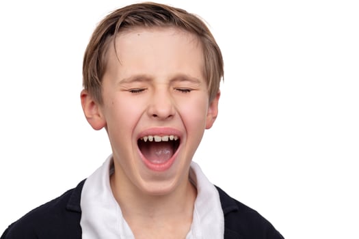 A close-up portrait of a boy who screams, opened his mouth. photo