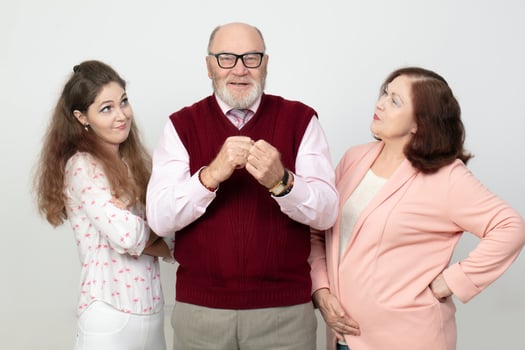A photo of a father being looked at reproachfully by an adult daughter and wife.