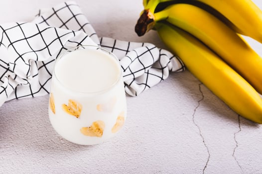Banana vegan alternative milk in glass and fruits on table photo