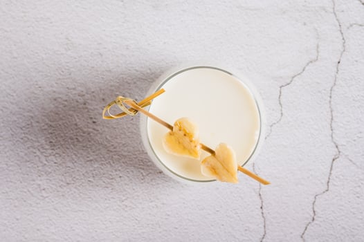 Close up of alternative lactose free banana milk in a glass on the table top view photo