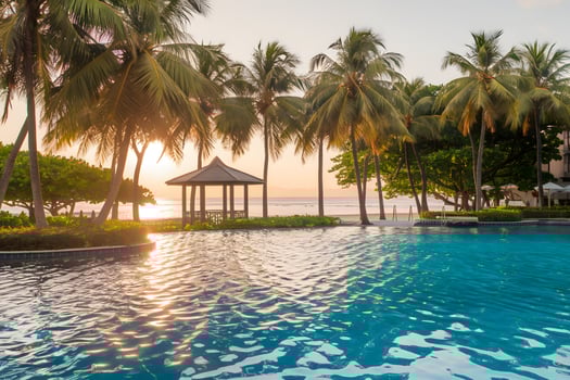 Luxury pool at sunset reflects golden light, palms complete tropical view photo