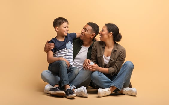 A loving African American family sits closely together, a father and mother enjoying quality time with their son. Smiles fill their faces as they embrace in a warm and inviting atmosphere. photo