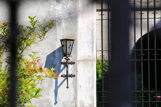 Historic outdoor wall lamp next to a grille gate photo