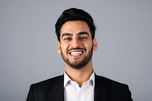 A Middle Eastern entrepreneur stands confidently, smiling in a corporate studio during a professional photoshoot. He embodies a modern lifestyle suited for business success. photo