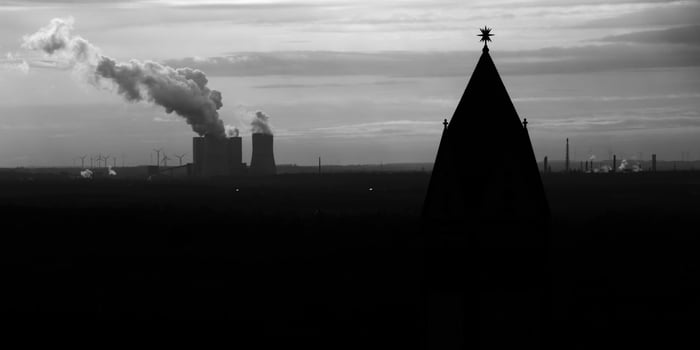 Silhouette of steeple and industrial power plant in background photo