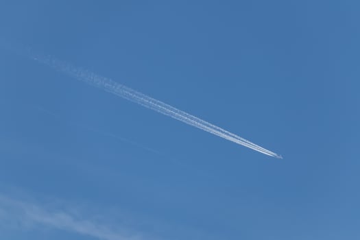 Contrails - one flying transport airplane with condensation trails in a blue sky photo