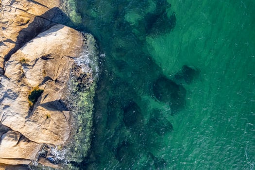 rocky coastline with turquoise sea water, aerial overhead view with drone photo
