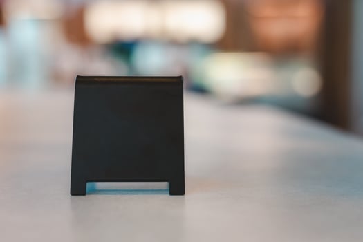 A blank black sign is placed on a cement table for Enter the text of your restaurant, store, or cafe. photo