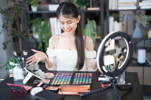 a beauty blogger woman is holding a makeup mirror and makeup products photo