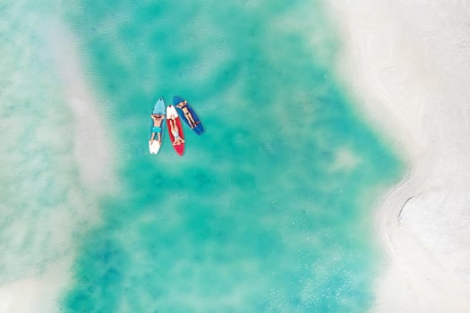 The family is resting lying on Sup boards in the turquoise sea. Three people ride sup boards in the ocean near the beach photo
