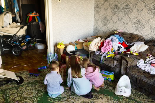 Three unrecognizable children are playing in a dirty cluttered room photo