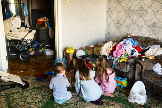Three unrecognizable children are playing in a dirty cluttered room photo