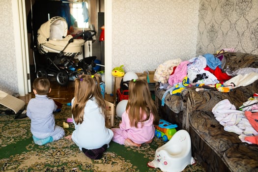 Three unrecognizable children are playing in a dirty cluttered room photo