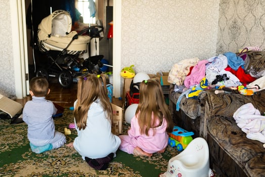 Three unrecognizable children are playing in a dirty cluttered room photo