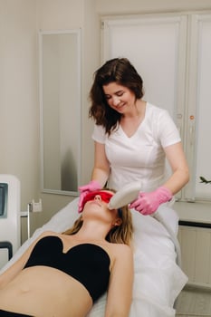 A doctor does laser hair removal for a client of unwanted facial hair in a beauty salon photo