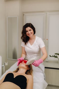 A doctor does laser hair removal for a client of unwanted facial hair in a beauty salon photo
