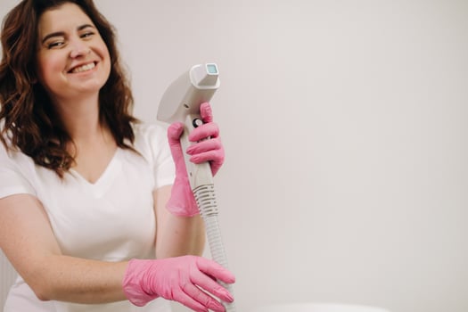 Portrait of the master of laser hair removal. A woman in a white coat holds a laser hair removal device in her hands photo