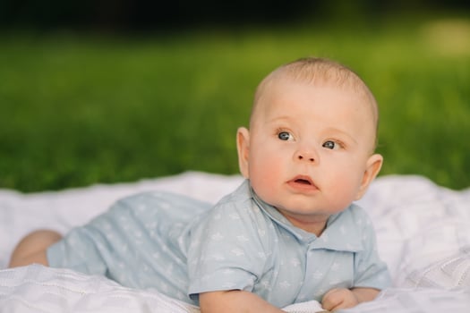 Cute happy toddler lying on a blanket on the grass outdoors in summer photo