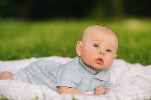 Cute happy toddler lying on a blanket on the grass outdoors in summer photo