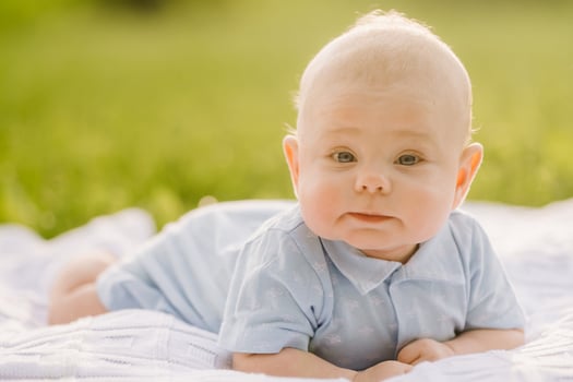 Cute happy toddler lying on a blanket on the grass outdoors in summer photo
