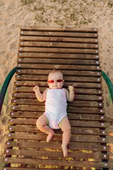 Top view of a happy little boy with glasses lying on a wooden sunbed photo