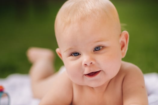 Cute happy toddler lying on a blanket on the grass outdoors in summer photo