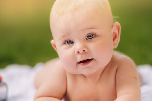 Cute happy toddler lying on a blanket on the grass outdoors in summer photo